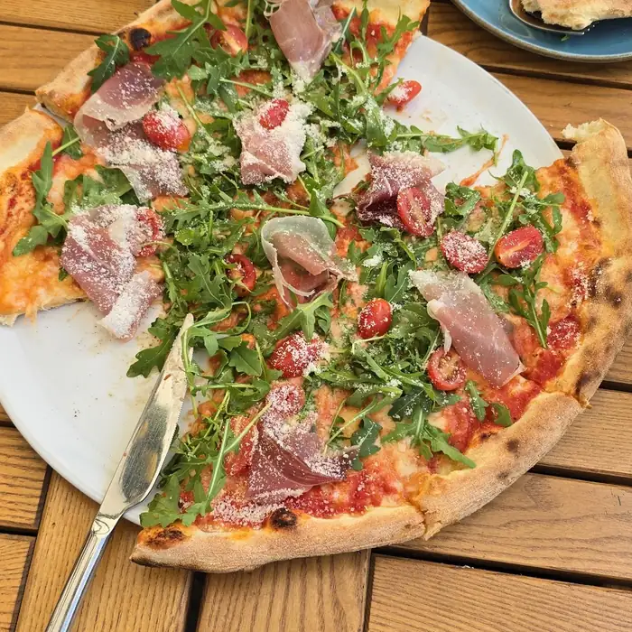Pizza z szynką parmeńską, rukolą i pomidorkami